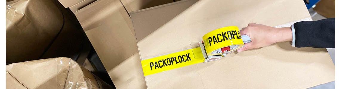 Tejp med packoplocks logotyp på en wellåda